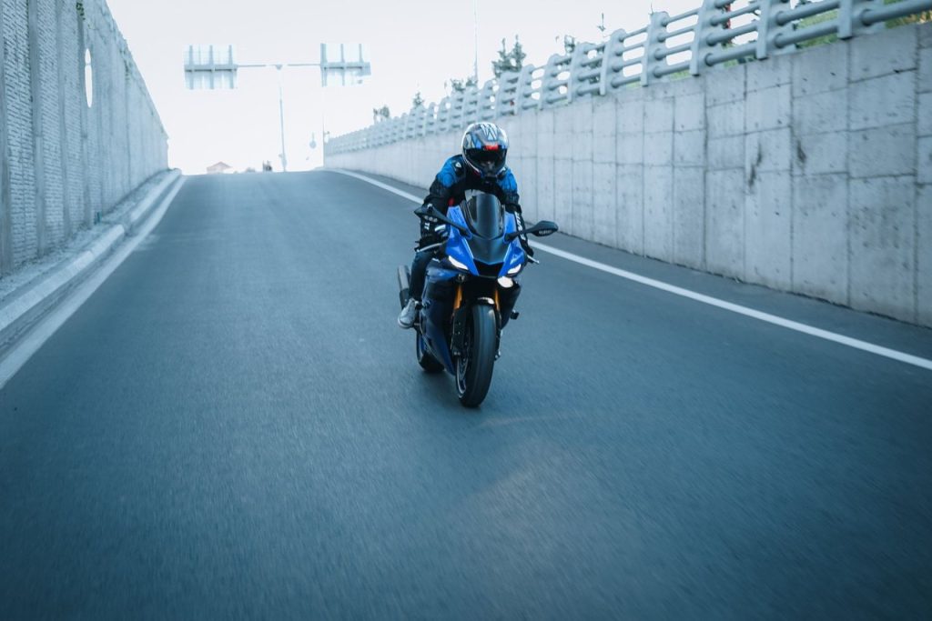 Motociclista usando capacete percorre uma rodovia pavimentada.
