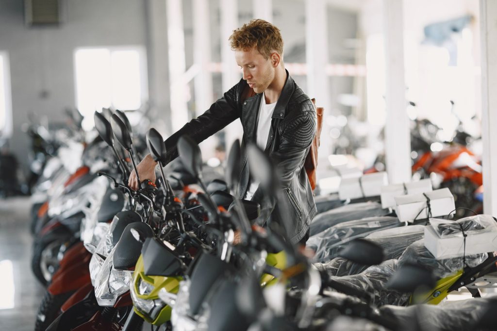 Mercado de motos fica estável em setembro, enquanto emplacamentos batem recorde Homem observa motocicletas novas expostas em uma concessionária.